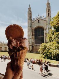 People holding ice cream cone against built structure