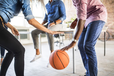 Colleagues playing basketball in office
