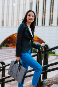 Portrait of beautiful young woman standing against railing