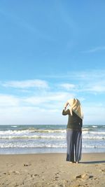 Rear view of man standing at beach against sky