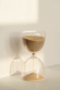 Transparent hourglass on a white sunny background.