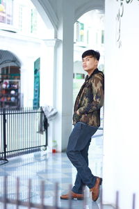 Side view of young woman standing against building