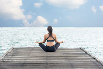 Full length of woman sitting on sea against sky