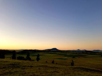 Scenic view of field against clear sky during sunset