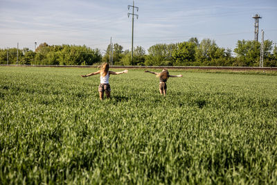 Friends enjoying on grassy field against sky