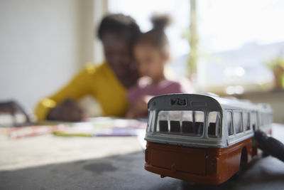 Toy bus on table, mother and daughter in background
