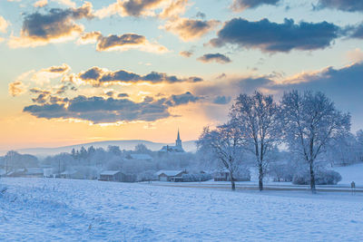 Scenic view of snow covered landscape against sky at sunset