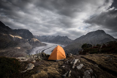 Tent on mountain against cloudy sky