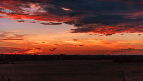 Scenic view of dramatic sky over field during sunset