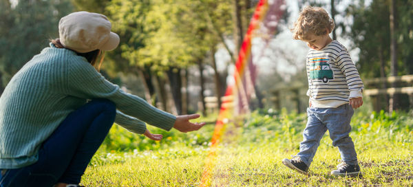 Rear view of mother playing with son at park