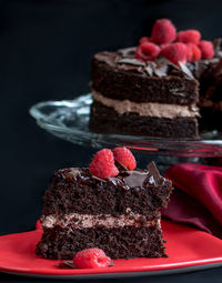 Close up of a decedent slice of chocolate cake with red raspberries