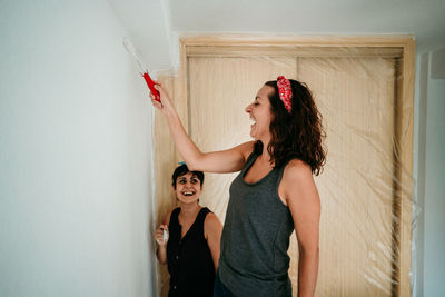 Smiling women painting wall at home