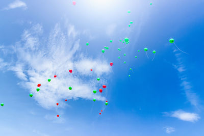 Low angle view of balloons flying against blue sky