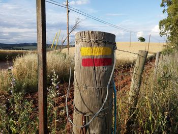 Wooden post on field against sky