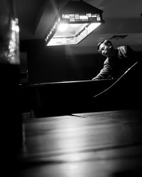 Side view of woman looking away while sitting in illuminated room