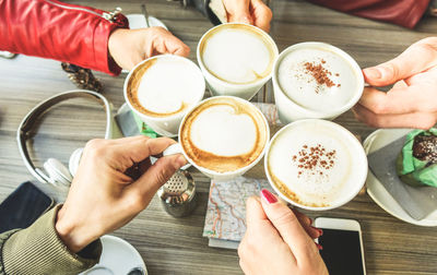 Cropped hands of people toasting coffee over table at restaurant