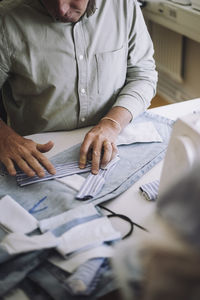 Midsection of male design professional examining fabric on jeans at workshop