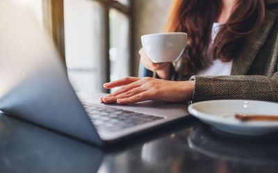 Midsection of woman holding coffee cup on table