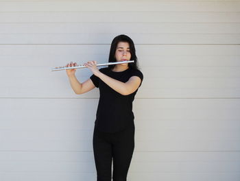 Full length of teenage girl playing against wall