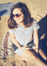 Portrait of beautiful young woman sitting on beach