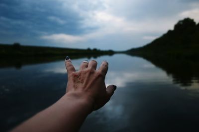 Close-up of hand against lake