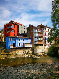 Buildings by lake against sky