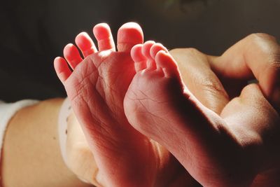 Cropped hands of parent holding newborn daughter legs