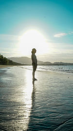 Shirtless man standing at beach against sky