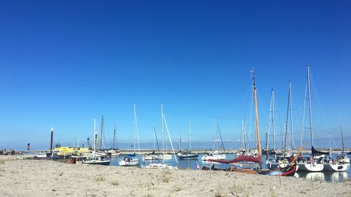 Sailboats moored on beach against clear blue sky