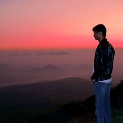 Side view of young man looking at sunset