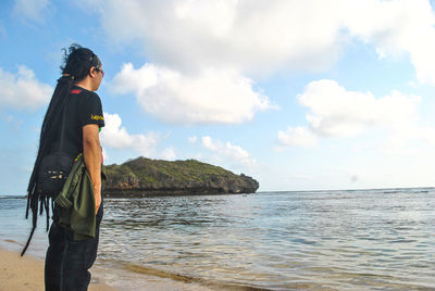 Side view of man standing in sea against sky