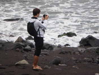 Full length of man photographing from camera at beach