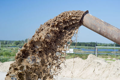 Close-up of metallic structure on field against clear sky