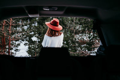 Rear view of woman wearing hat seen through car outdoors