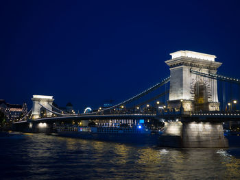 Illuminated bridge over river at night