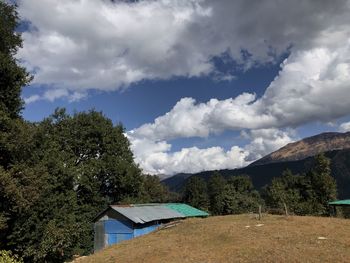 Houses and trees by mountains against sky