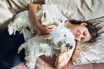 Woman with dog lying on bed at home