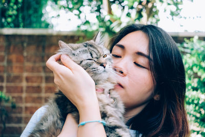 Beautiful young woman with cat with eyes closed