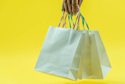 Midsection of woman holding umbrella against yellow background