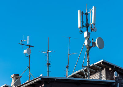 Low angle view of communications tower against clear blue sky