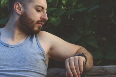 Young man looking away while sitting outdoors