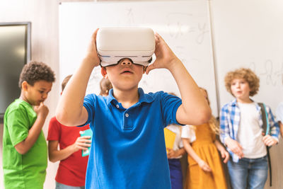 Cute boy using virtual reality simulator in classroom