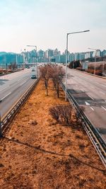 Road by bridge in city against sky