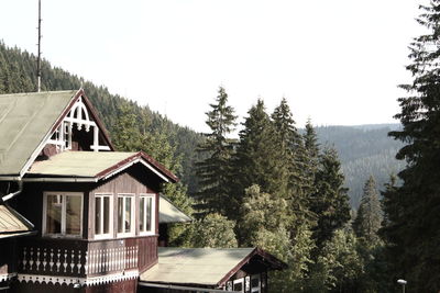 House amidst trees and buildings against clear sky