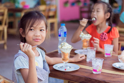 Portrait of smiling girl with ice cream on table