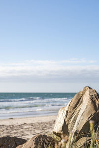 Close-up of rock set against scenic beach side view of sea against sky