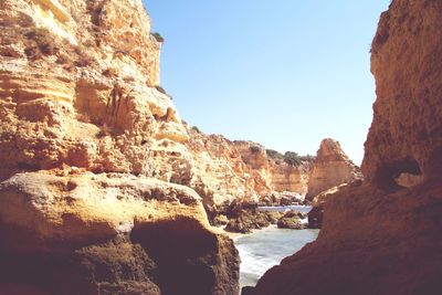 Rock formations by sea against clear sky