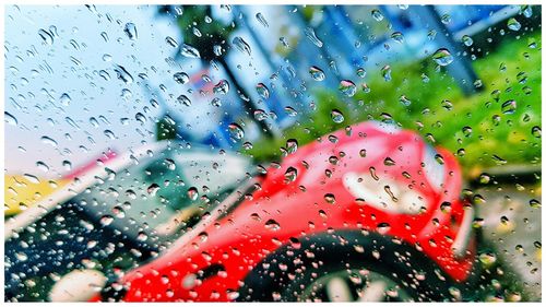 Close-up of water drops on window against sky