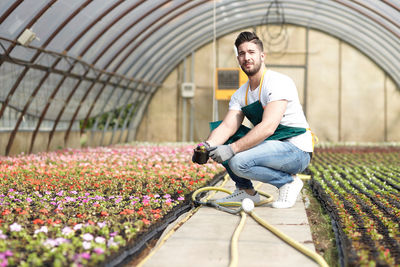 Full length portrait of man working in greenhouse