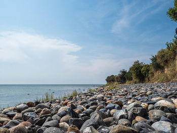 Rocks on shore by sea against sky